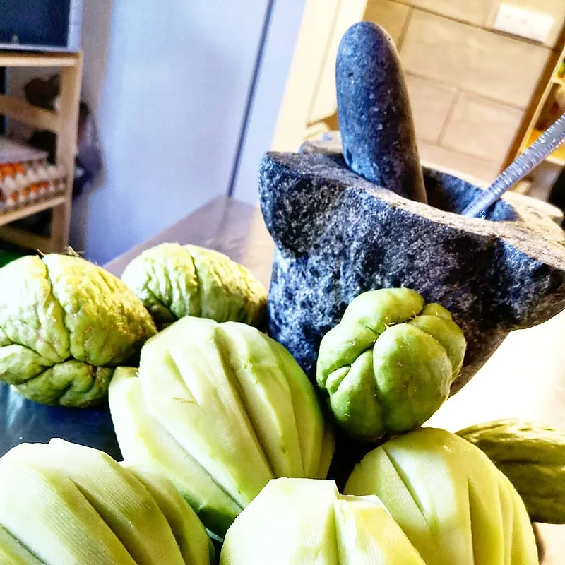 Des chouchous de La Réunion près d'un pilon en pierre