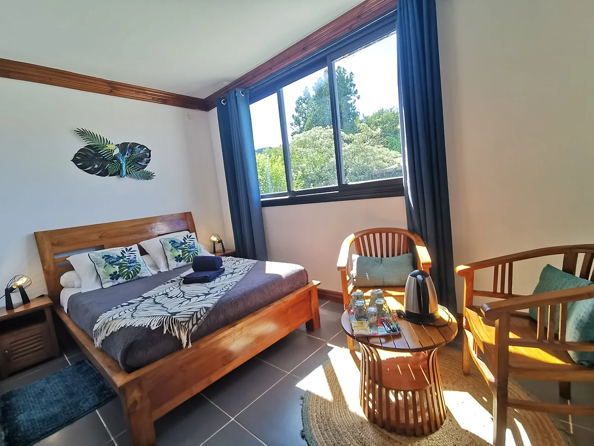 La chambre double standard, son lit en bois et ses deux fauteuils en rotin