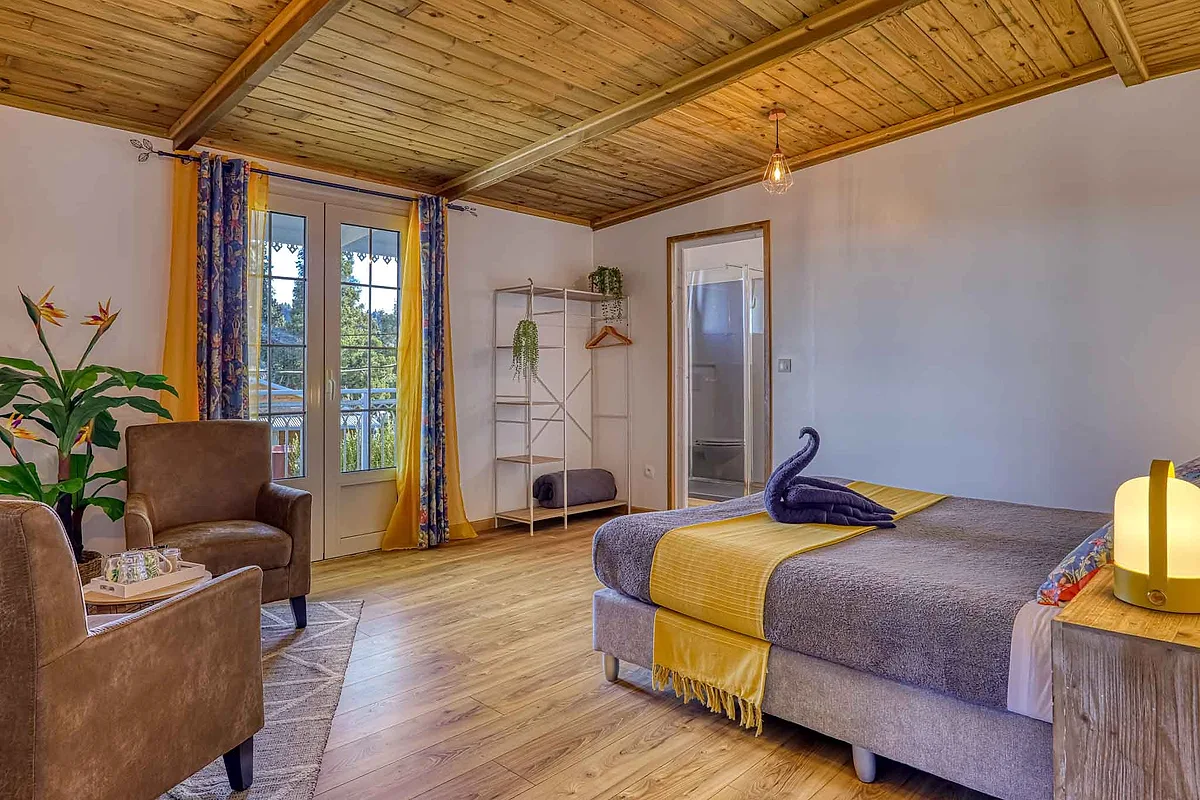 La chambre supérieure, son plafond en bois, son lit et son coin salon